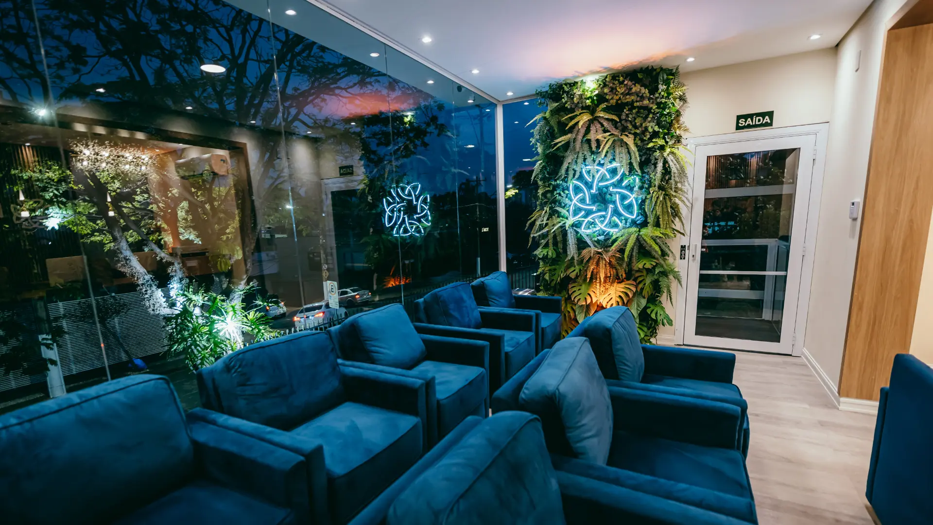 Sala de espera da Dimaze com poltronas azuis e jardim vertical iluminado